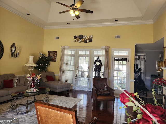 living room with visible vents, wood finished floors, a high ceiling, and ornamental molding