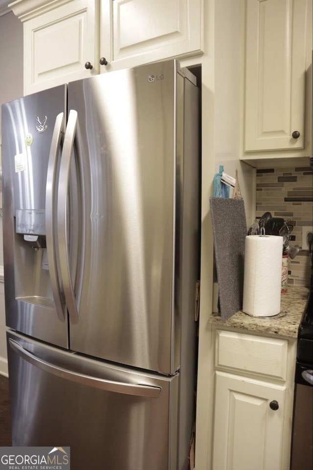 kitchen featuring decorative backsplash, light stone countertops, stainless steel fridge with ice dispenser, and white cabinetry