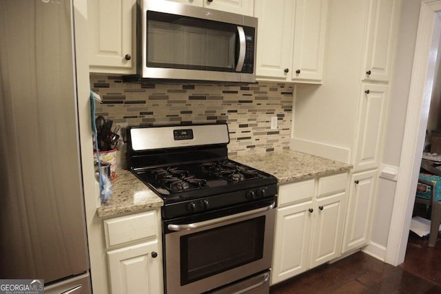 kitchen with white cabinets, light stone countertops, tasteful backsplash, and stainless steel appliances