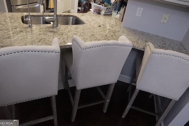 interior space with refrigerator, light stone countertops, and a sink