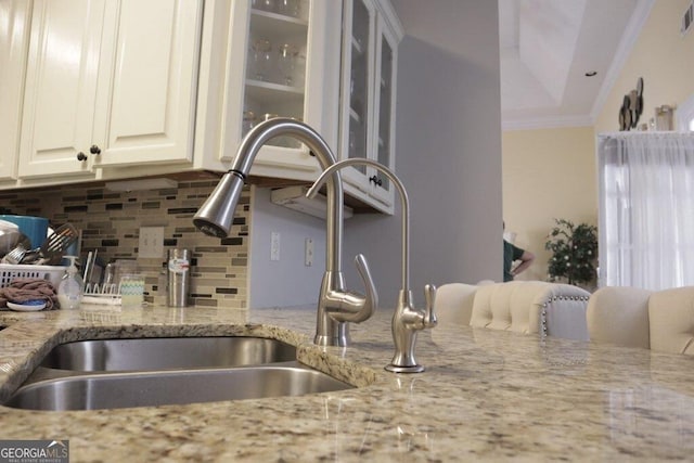 interior details with visible vents, ornamental molding, a sink, decorative backsplash, and light stone countertops