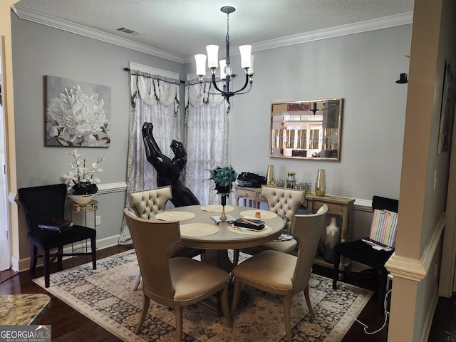 dining area featuring wood finished floors, visible vents, ornamental molding, a textured ceiling, and a notable chandelier