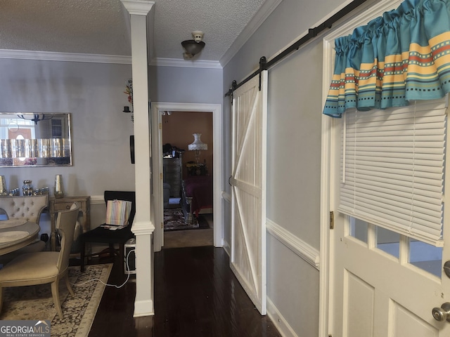 hall featuring a textured ceiling, a barn door, dark wood-style flooring, and ornamental molding