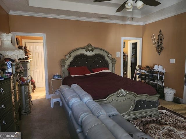 bedroom with visible vents, ceiling fan, ornamental molding, a raised ceiling, and carpet flooring