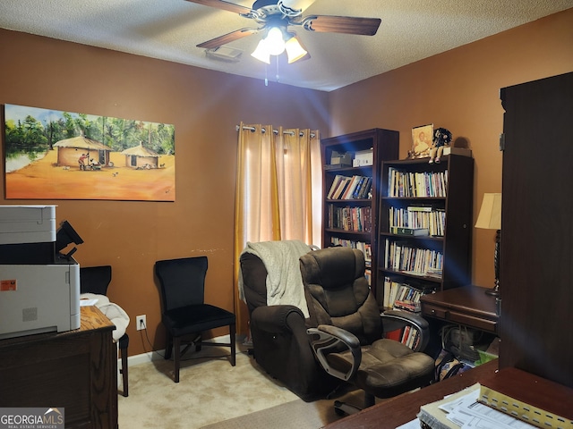 carpeted home office featuring baseboards, a textured ceiling, and ceiling fan