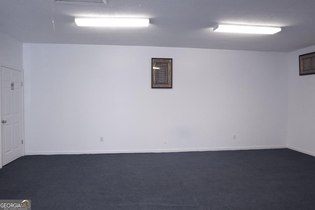 empty room featuring a textured ceiling and dark colored carpet