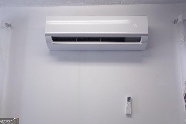 interior details with a wall mounted air conditioner and a textured ceiling