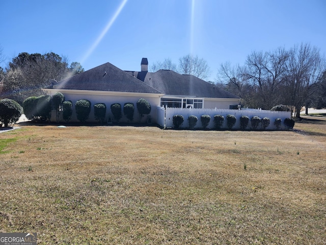 view of side of home featuring fence, a lawn, and a chimney