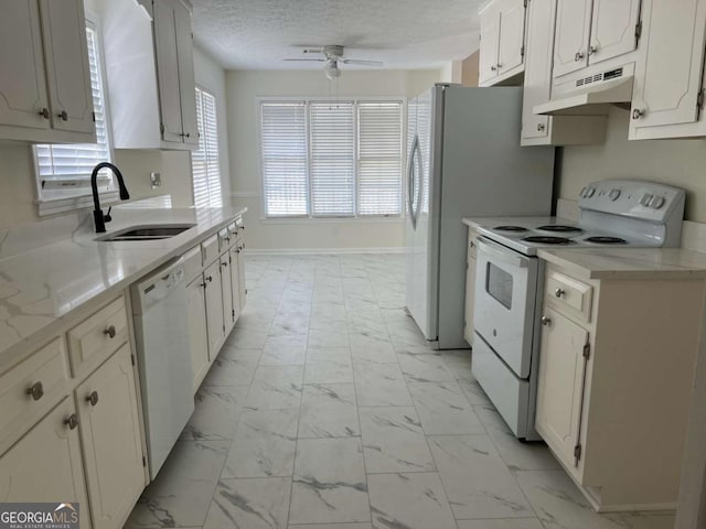 kitchen with marble finish floor, light countertops, a sink, white appliances, and under cabinet range hood