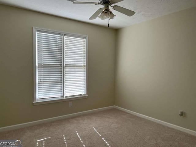 carpeted spare room featuring a textured ceiling, a ceiling fan, and baseboards