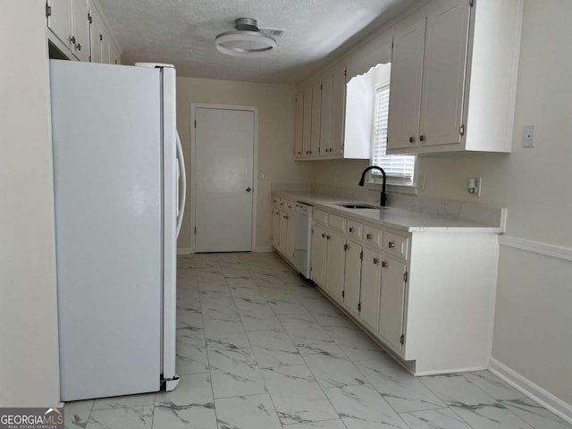 kitchen with a textured ceiling, white appliances, a sink, marble finish floor, and light countertops