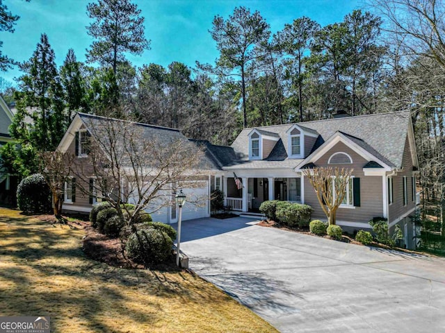 cape cod home featuring a garage, a porch, concrete driveway, and a front yard