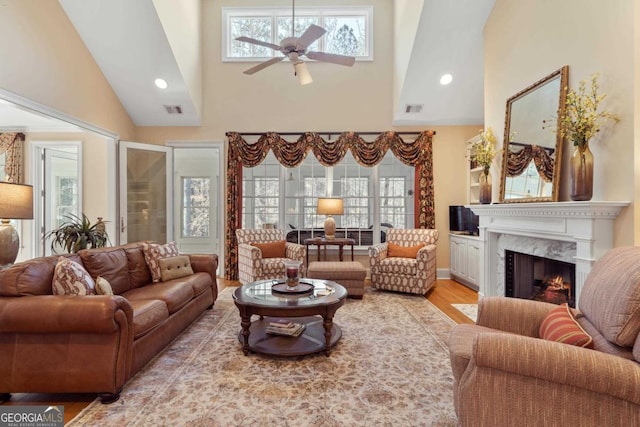 living room with light wood-style floors, visible vents, a fireplace, and a ceiling fan