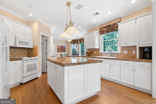 1020 Troublesome Creek Ln, Greensboro, GA 30642 - kitchen featuring ornamental molding, a kitchen island, white appliances, and white cabinetry