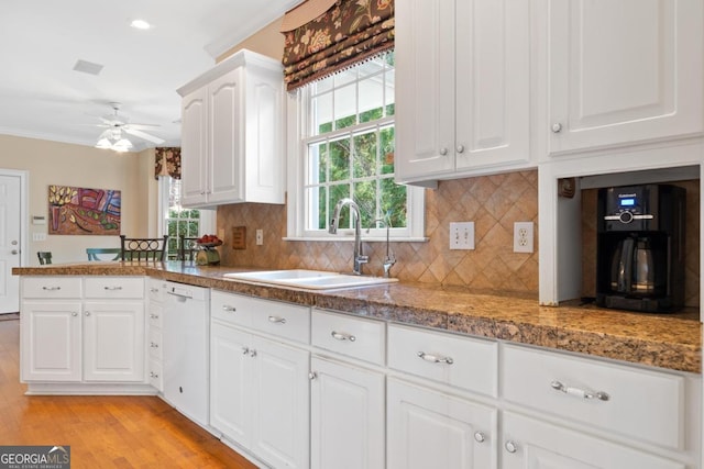 kitchen featuring white cabinets, dishwasher, light wood-style flooring, a peninsula, and a sink