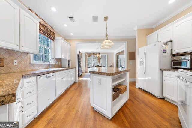 kitchen with a center island, open shelves, visible vents, a sink, and white appliances