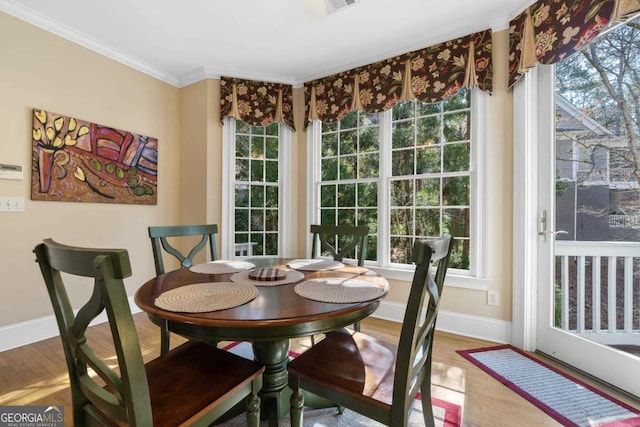 dining space with baseboards, wood finished floors, and crown molding