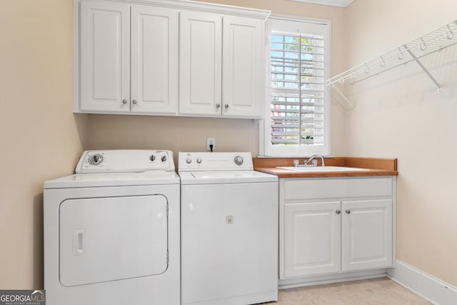 laundry room featuring cabinet space, baseboards, washer and dryer, and a sink