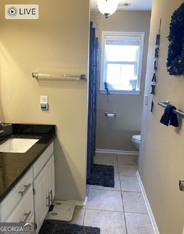 full bathroom featuring toilet, tile patterned flooring, baseboards, and vanity