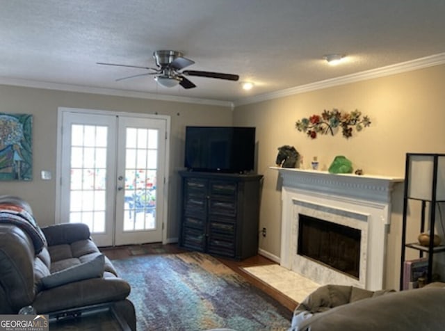 living room featuring a fireplace, wood finished floors, a ceiling fan, ornamental molding, and french doors