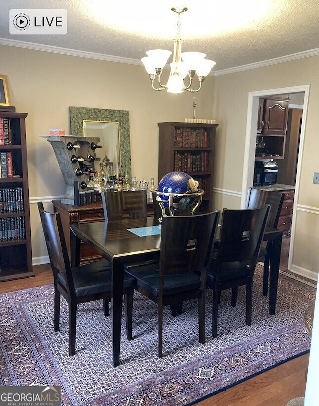 dining area with wood finished floors, crown molding, a textured ceiling, and an inviting chandelier