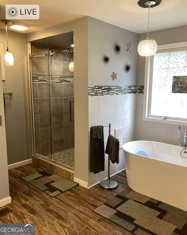 bathroom with a stall shower, a freestanding tub, tile walls, and wood tiled floor