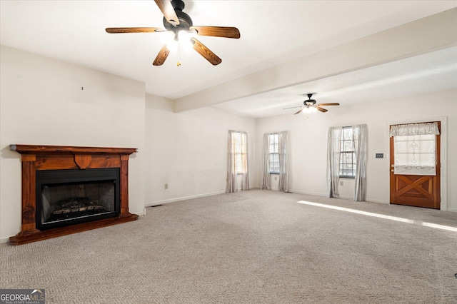 unfurnished living room featuring ceiling fan, carpet, baseboards, and a fireplace with raised hearth