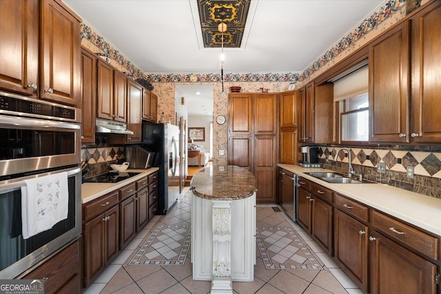 kitchen featuring wallpapered walls, light tile patterned floors, appliances with stainless steel finishes, under cabinet range hood, and a sink