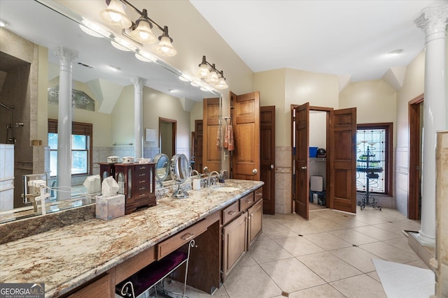 bathroom featuring a wainscoted wall, vaulted ceiling, tile walls, and ornate columns