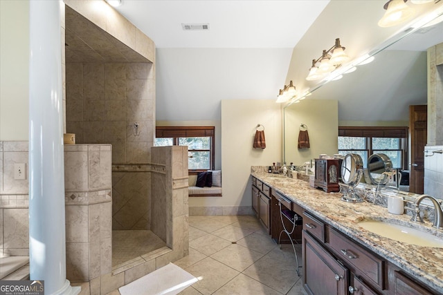 full bathroom with double vanity, visible vents, a sink, tiled shower, and tile patterned floors