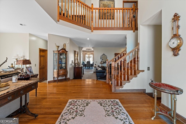 foyer featuring a towering ceiling, stairs, baseboards, and wood finished floors