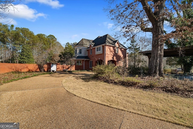 view of front of property with brick siding, driveway, and fence