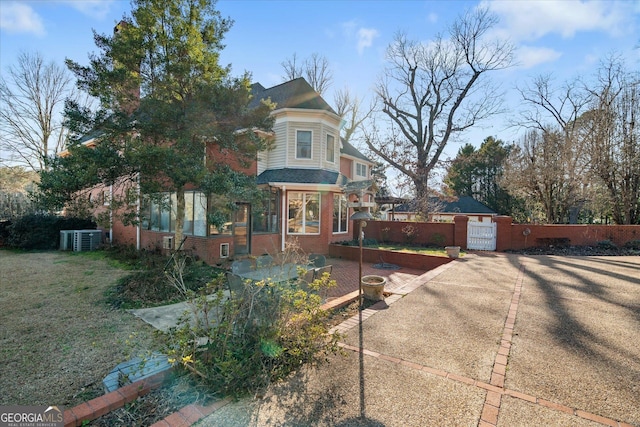 view of front of property featuring brick siding, fence, a gate, and central air condition unit