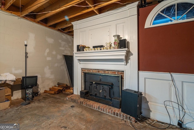 living room featuring concrete block wall, a wood stove, and concrete floors