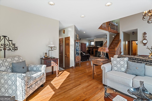 living room with recessed lighting, a fireplace, light wood finished floors, and stairs