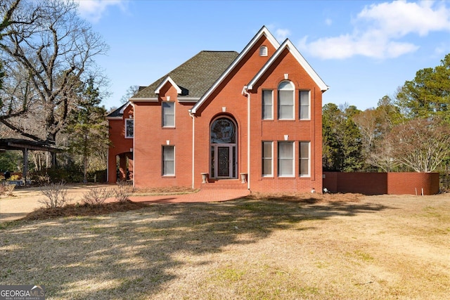 traditional-style house featuring fence, a front lawn, and brick siding