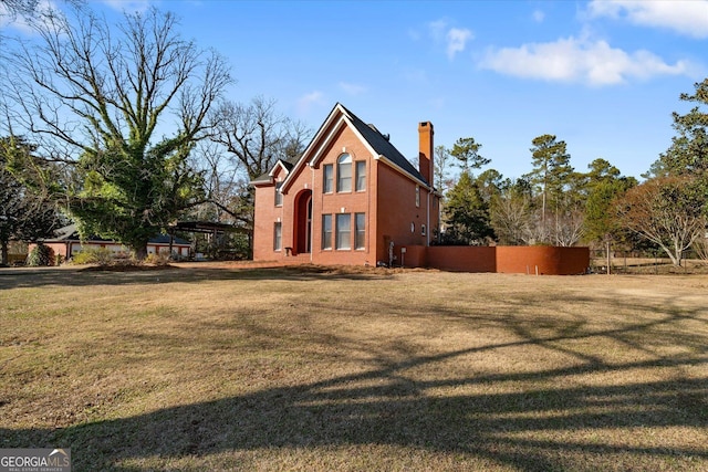 exterior space with a chimney, fence, and a lawn