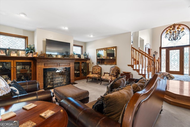 carpeted living room with a fireplace with flush hearth, stairway, and an inviting chandelier