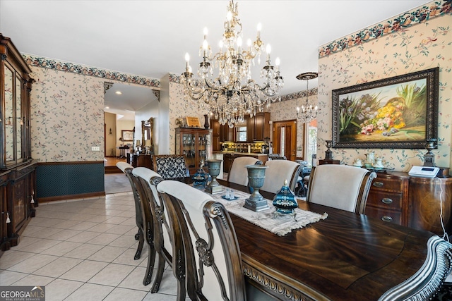 dining room with wallpapered walls, light tile patterned flooring, a notable chandelier, and a wainscoted wall