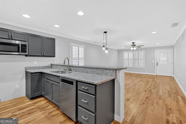 kitchen with visible vents, a peninsula, stainless steel appliances, crown molding, and a sink