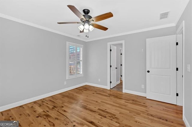 unfurnished bedroom featuring light wood finished floors, baseboards, visible vents, ceiling fan, and crown molding