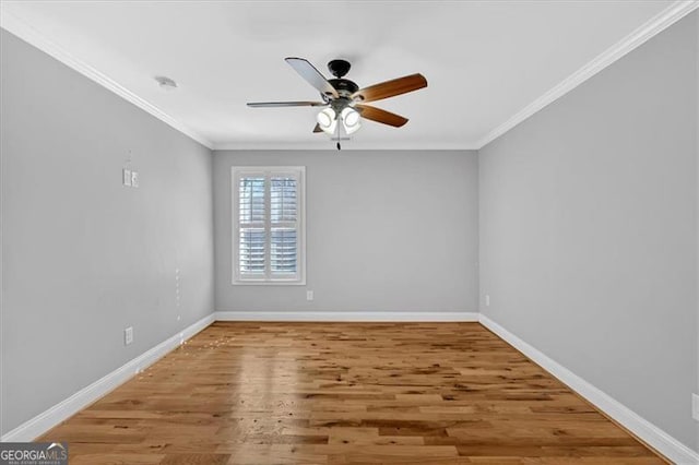 spare room with ornamental molding, ceiling fan, baseboards, and wood finished floors