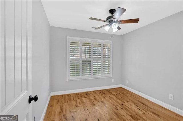 spare room featuring wood finished floors, a ceiling fan, and baseboards