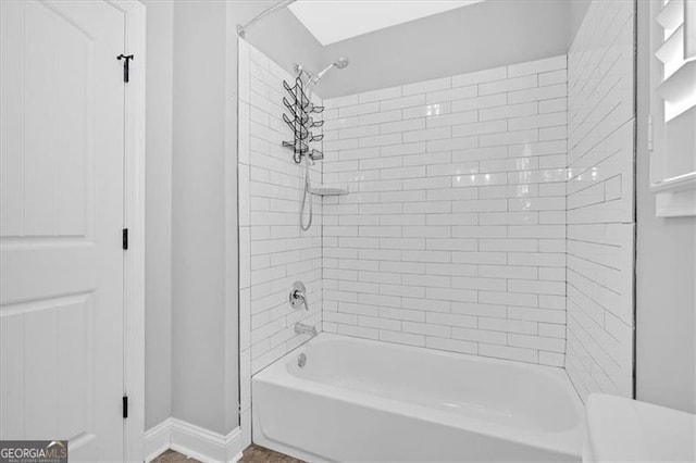 bathroom with bathtub / shower combination and baseboards