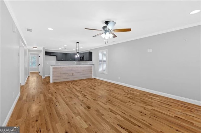 unfurnished living room with visible vents, baseboards, light wood-style flooring, and crown molding