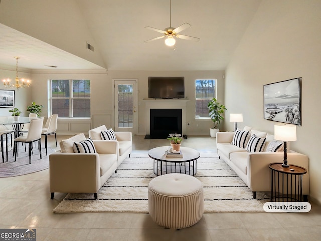 tiled living room featuring high vaulted ceiling, visible vents, a fireplace, and ceiling fan with notable chandelier