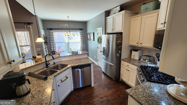 kitchen featuring decorative backsplash, light stone counters, dark wood-type flooring, stainless steel appliances, and a sink