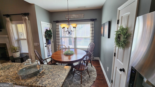 dining area with dark wood-style floors, a fireplace, visible vents, an inviting chandelier, and baseboards
