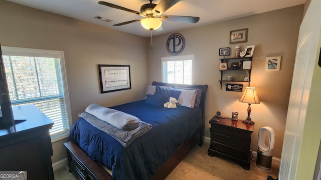 carpeted bedroom featuring a ceiling fan, visible vents, and baseboards