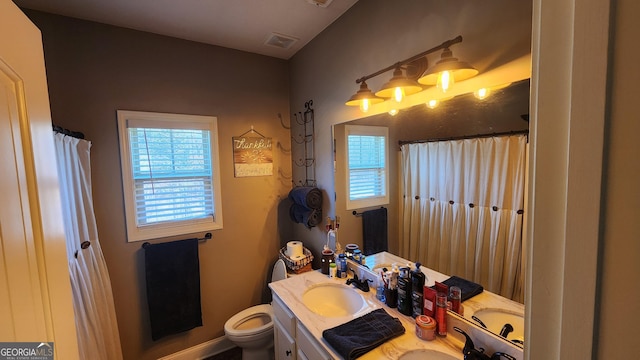 bathroom with toilet, a shower with shower curtain, vanity, and visible vents